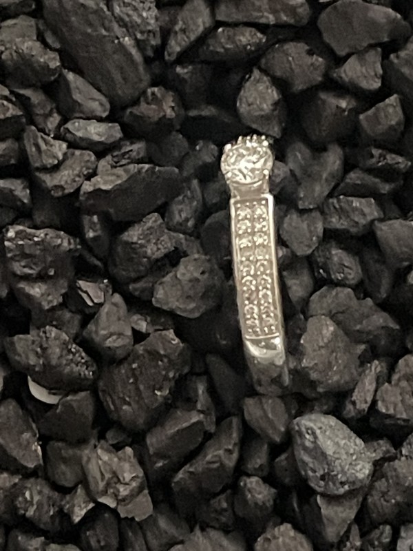 Un solitaire diamant accompagné, monté en or blanc 18K, avec un pavage délicat sur l’anneau, pour un total de 0,35 carats, pour une bague de fiançailles