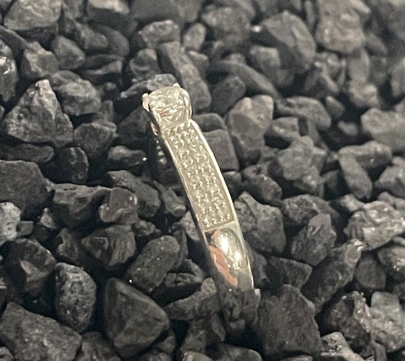 Un solitaire diamant accompagné, monté en or blanc 18K, avec un pavage délicat sur l’anneau, pour un total de 0,35 carats, pour une bague de fiançailles